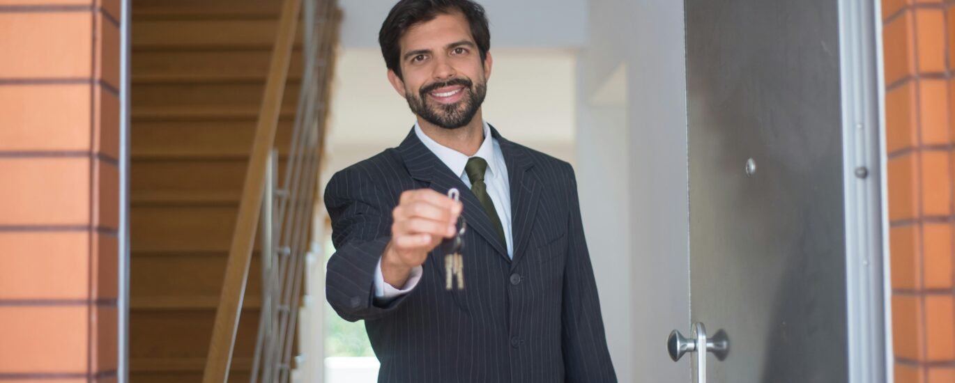 A man holding house keys with tears in his eyes, standing in front of a modern Dubai villa