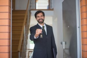 A man holding house keys with tears in his eyes, standing in front of a modern Dubai villa